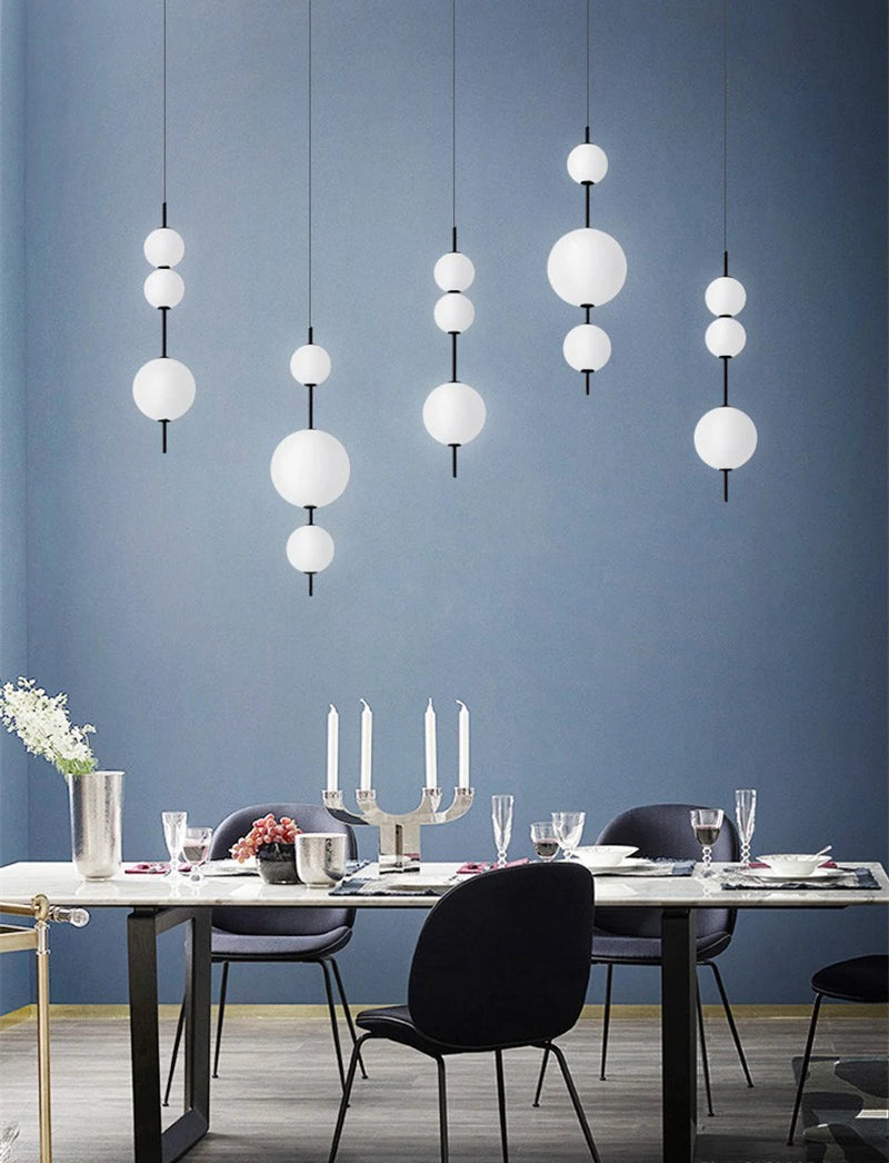 Modern dining room with white pendant lights against a blue wall.