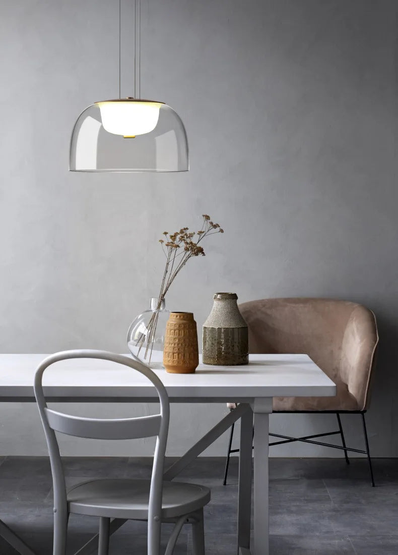 Modern dining area with a white table, gray chairs, and a pendant light.