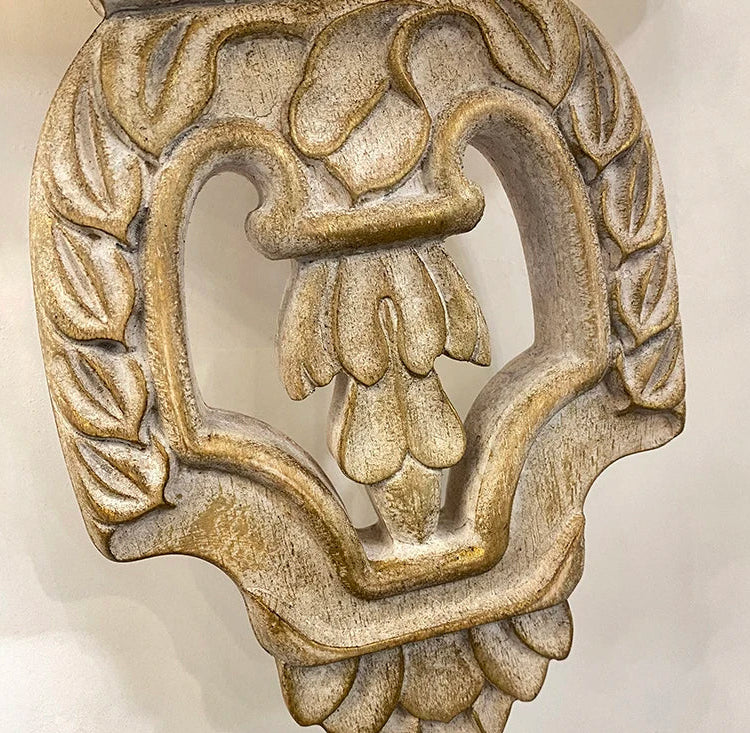 Decorative metal knocker with floral design on a beige background.