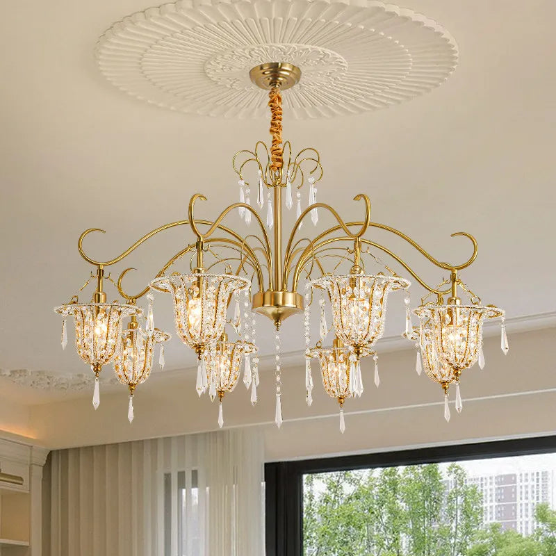Close-up of the gold crystal chandelier showing the intricate arms, crystal droplets, and bell-shaped light shades.