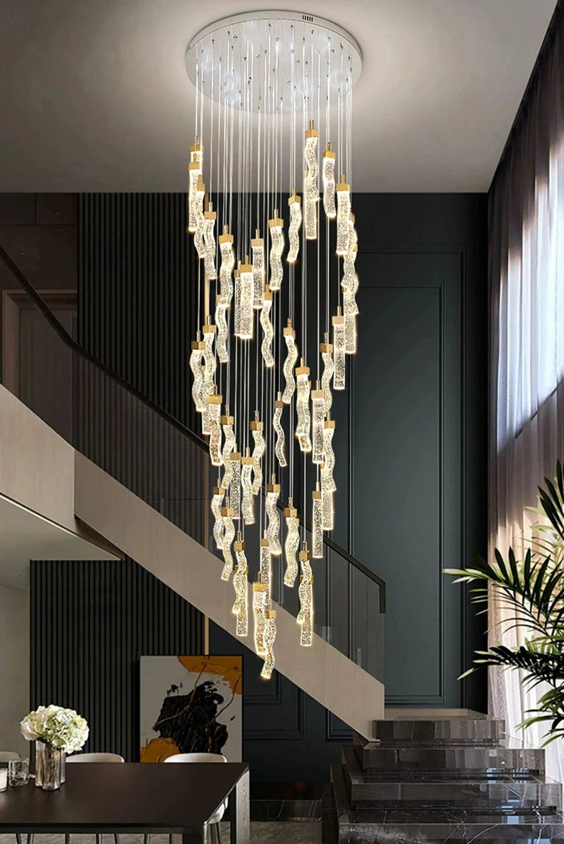 Luxurious chandelier hanging in a modern interior setting with a staircase and decor elements.