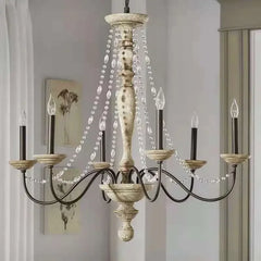 A detailed shot of the distressed wood central column and candle-style lights of a crystal chandelier.