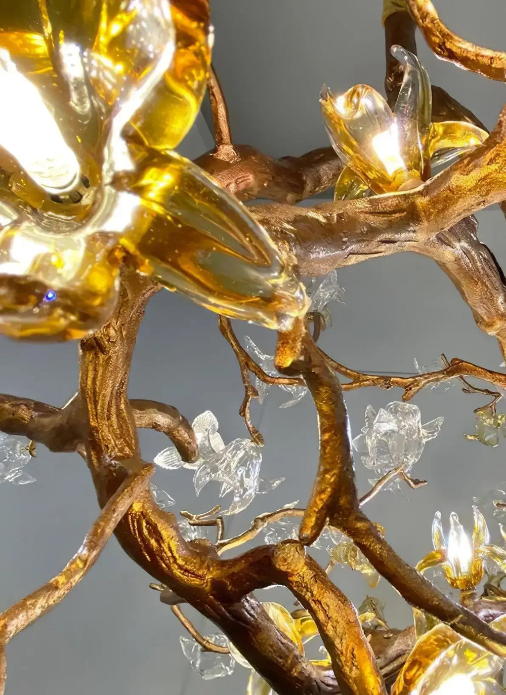 Decorative chandelier with gold branches and crystal-like elements on a gray background