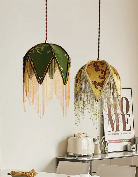 Two pendant lights, one yellow floral and one green bamboo, hanging side-by-side.