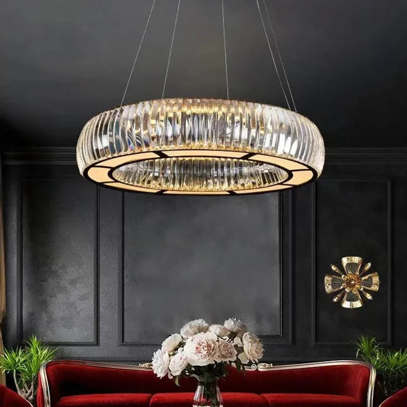 Circular chrome pendant light with clear crystals, suspended from the ceiling in a dimly lit room.