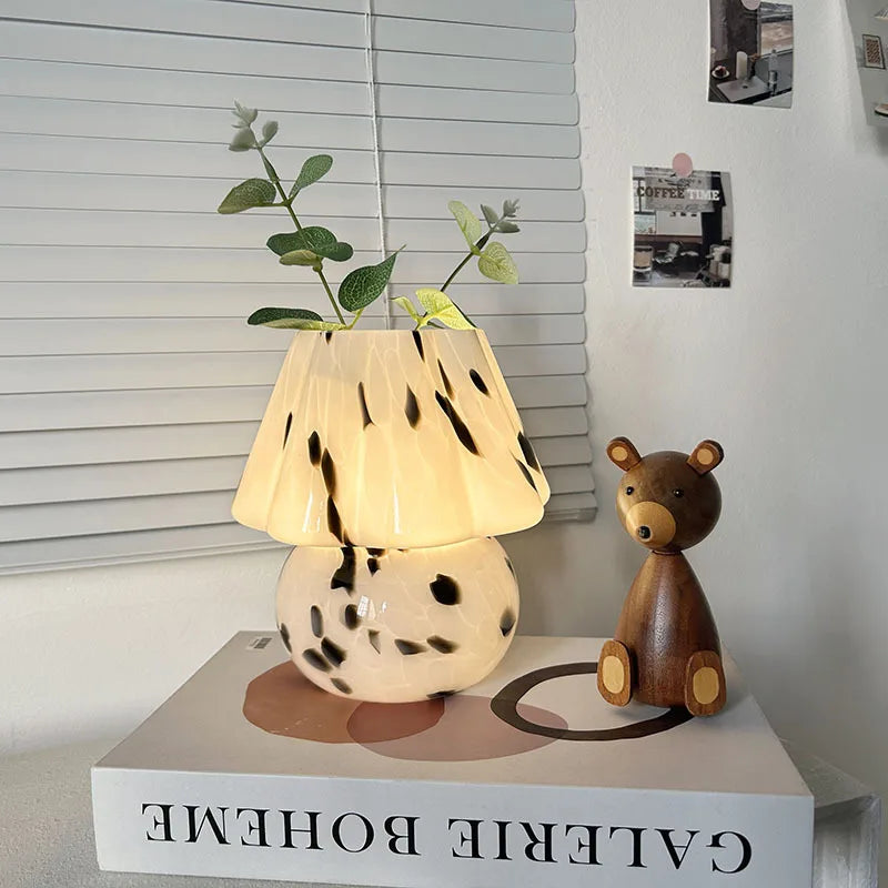Decorative lamp with a plant and wooden bear on a book titled 'Galerie Boheme'.