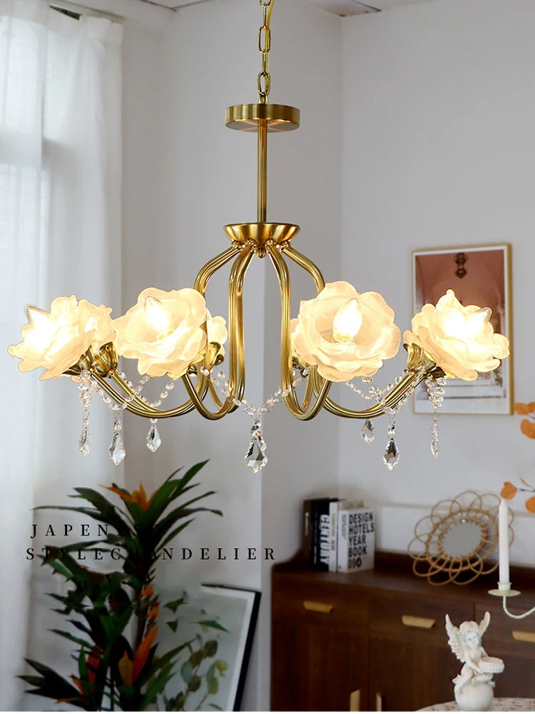 Gold metal chandelier with five rose-shaped lampshades and crystal teardrop pendants hanging from curved arms.