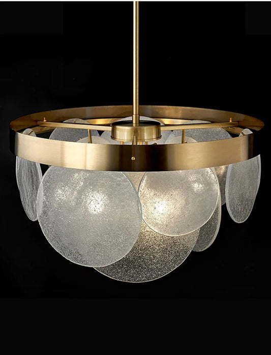 Close-up of a gold glass disc chandelier pendant light against a black background, highlighting the textured glass.