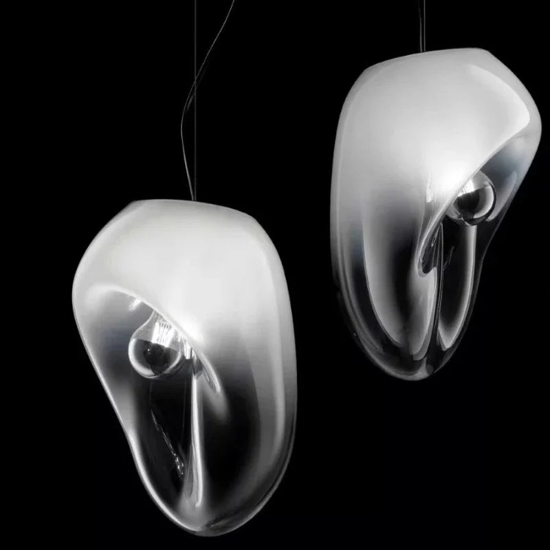 Two smoke gray glass organic shape pendant lights against a black background.