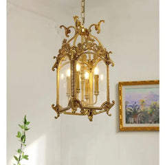 Close-up of the top section of a gold candelabra cage pendant light, highlighting the decorative scrollwork and chain.