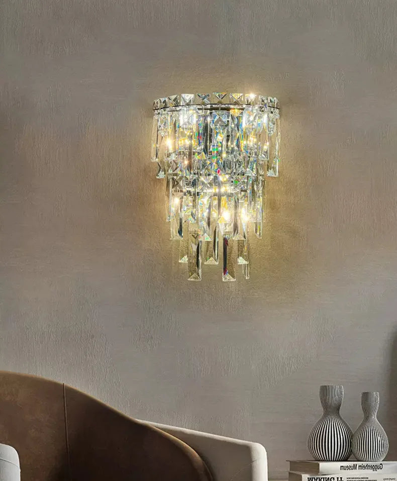 Crystal wall sconce on a neutral wall with a sofa and decorative vases in the foreground.