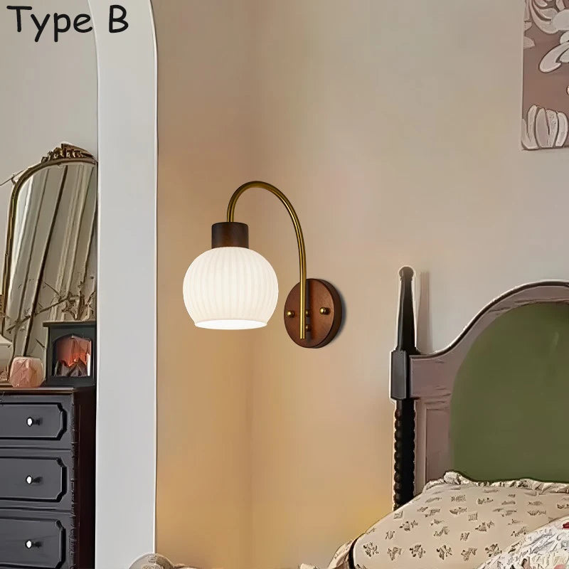 Close-up of a wall sconce with a wood base and a ribbed glass shade mounted on an adjustable brass arm.