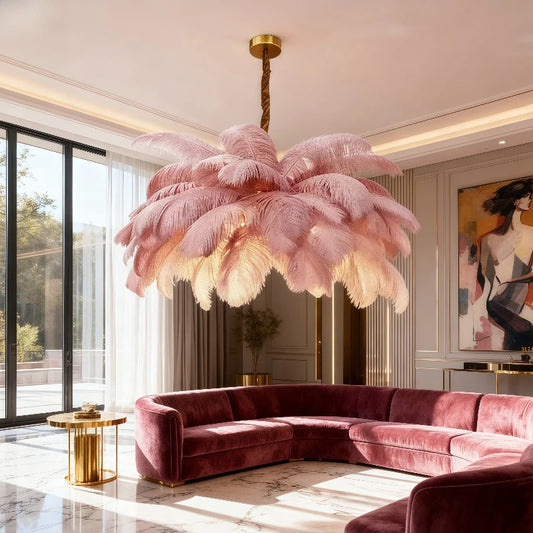 Pink feather chandelier with gold accents hanging in a modern living room above a velvet sectional sofa.