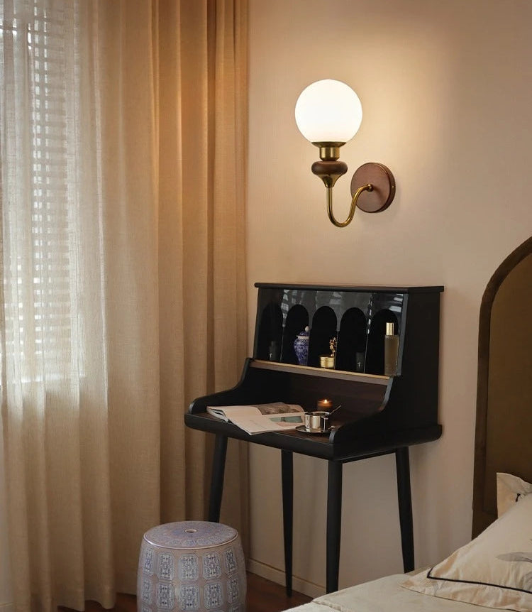 Room interior with a wall sconce, desk, and bed, evoking an antique atmosphere.