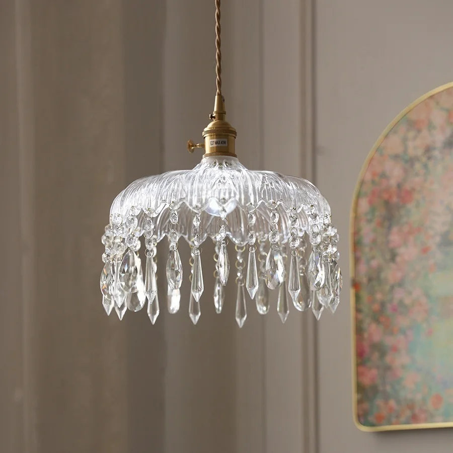 Decorative glass pendant light with crystal details on a neutral wall.
