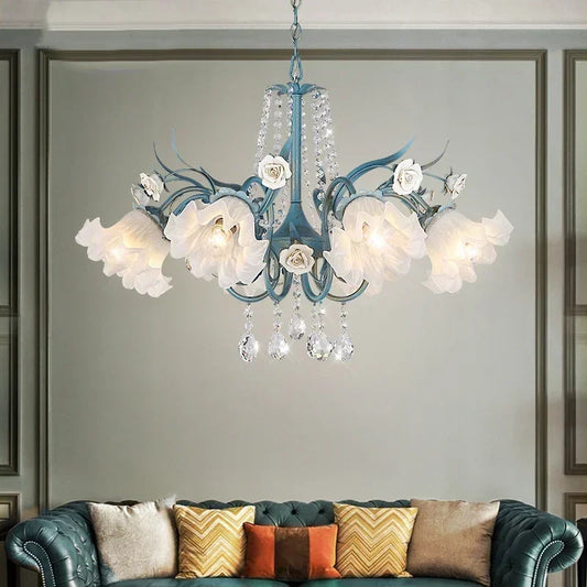 Blue floral ceramic chandelier with crystal accents and polished chrome finish, hanging above a teal sofa.