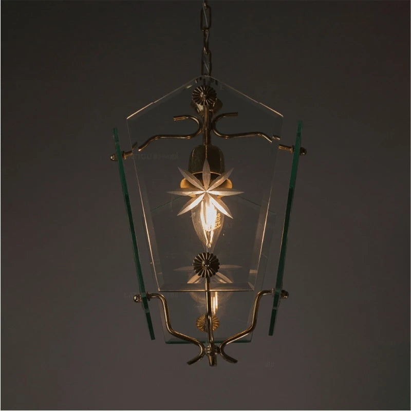 Close-up of a clear glass pendant light with etched starburst patterns and brass accents, showing the bulb.