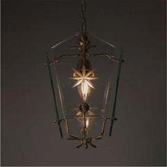 Close-up of a clear glass pendant light with etched starburst patterns and brass accents, showing the bulb.
