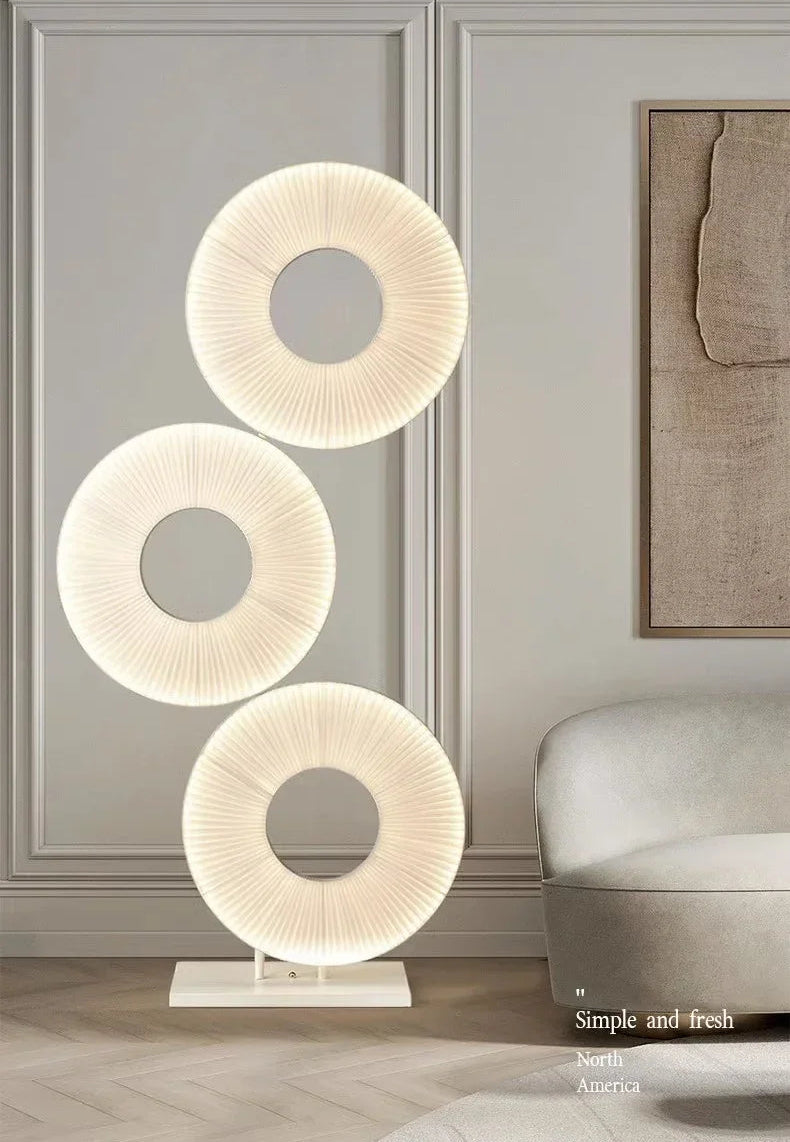 Modern floor lamp with three circular designs in a room setting.