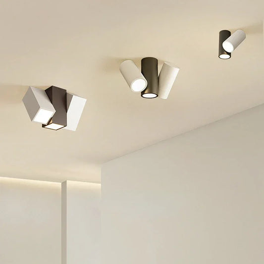 Modern black and white cylinder spotlights mounted on a ceiling, with adjustable heads.