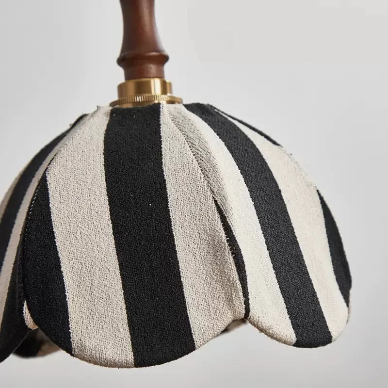 Detailed view of the top of the pendant light, showing the connection between the wooden stem, brass hardware, and the fabric shade.