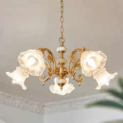 Close-up view of a gold chandelier with frosted glass flower-shaped shades, showcasing the ornate details and central stem.