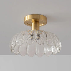 A flush mount ceiling light with a gold metal base and a decorative clear glass shade that resembles layered petals.