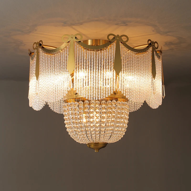 A gold and crystal tiered chandelier mounted on a ceiling, illuminated with warm light.