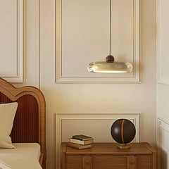 Decorative lamp hanging above a wooden nightstand with books and a globe in a bedroom setting.