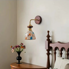 A wood and glass shell wall sconce mounted on a wall next to a wooden headboard.