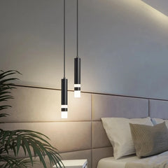 Black cylindrical pendant light with a white light strip, shown in a bedroom setting.