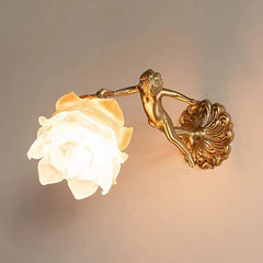 A copper wall sconce featuring a frosted flower glass shade with a small copper cherub figure attached to a decorative base.