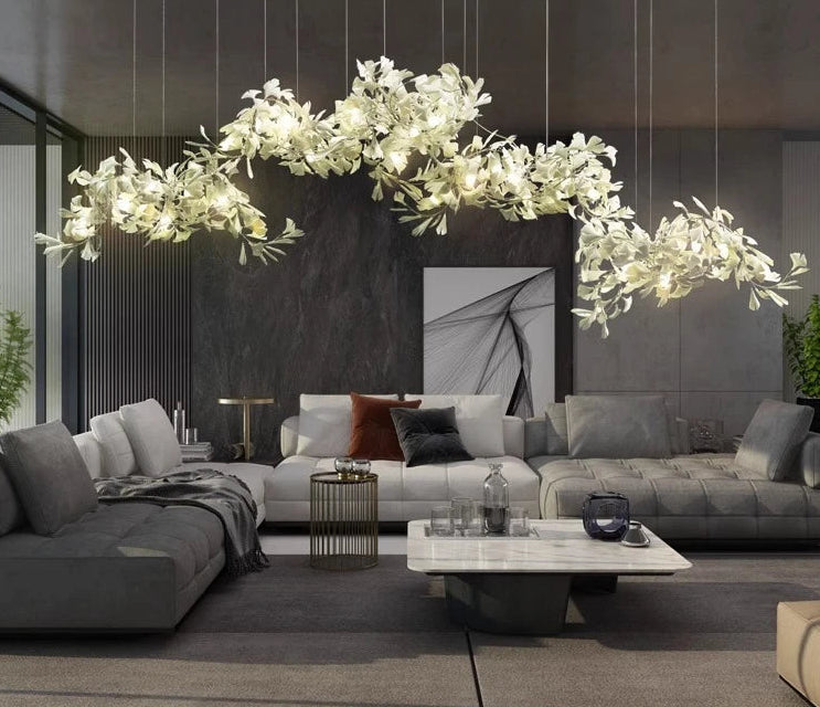 Modern living room with gray sectional sofa, decorative plants, and a stylish chandelier.