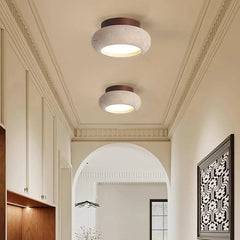 A contemporary hallway featuring two round yellow travertine flush mount ceiling lights with dark wood canopies.