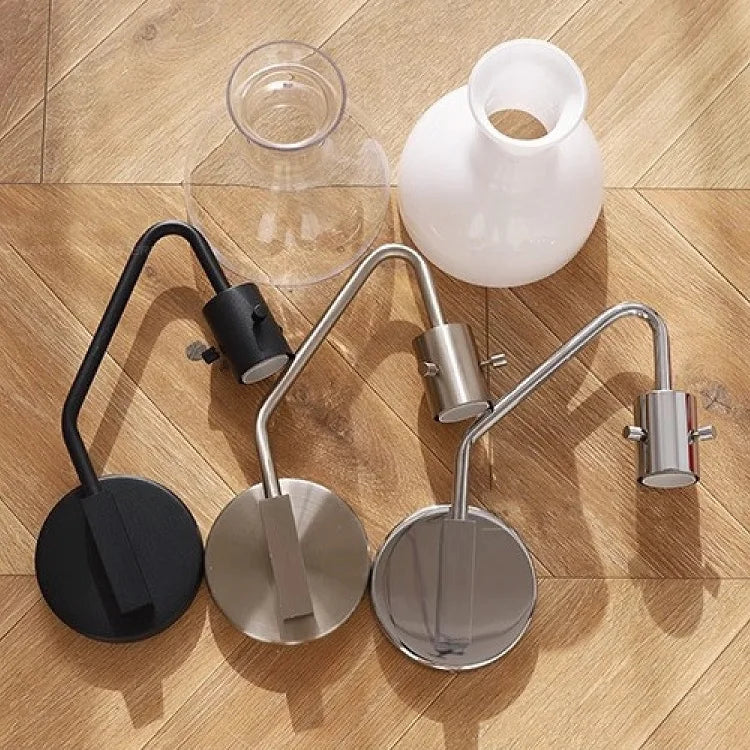 Two wall-mounted lamps on a wooden floor with a glass and a white vase.