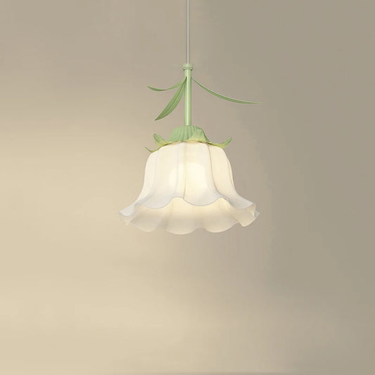 Close-up of a white frosted glass pendant light shaped like a flower bud with green stem and leaves, hanging against a cream-colored wall.