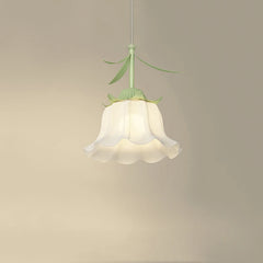 Close-up of a white frosted glass pendant light shaped like a flower bud with green stem and leaves, hanging against a cream-colored wall.
