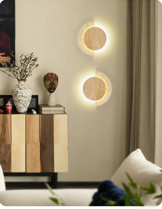 Two modern wall sconces with wood circles and speckled stone arcs mounted on a wall in a living space.