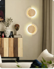 Two modern wall sconces with wood circles and speckled stone arcs mounted on a wall in a living space.