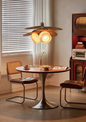 Dining area with a round table, chairs, and a pendant light in a room with a window and vintage decor.