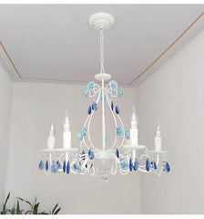 Low-angle view of a white semi-flush mount chandelier with blue floral details and crystal prisms, mounted on a white ceiling.