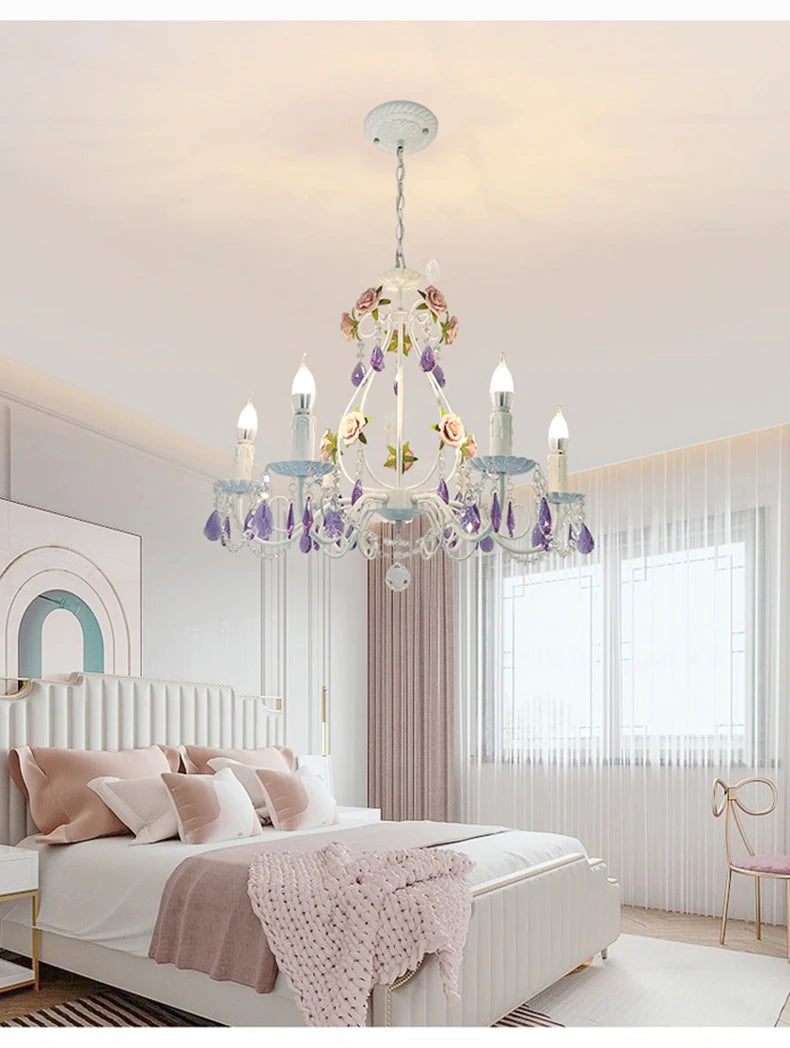 Close-up of a white chandelier featuring pink rose embellishments and cascading purple crystals.