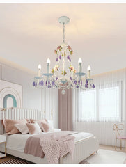 Close-up of a white chandelier featuring pink rose embellishments and cascading purple crystals.