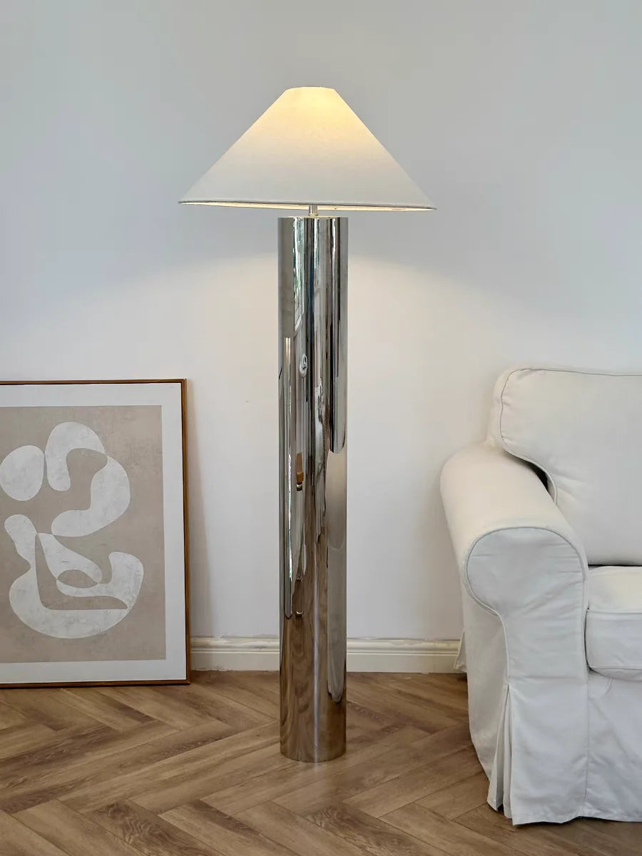 Floor lamp in a room with a sofa and artwork on the wall.