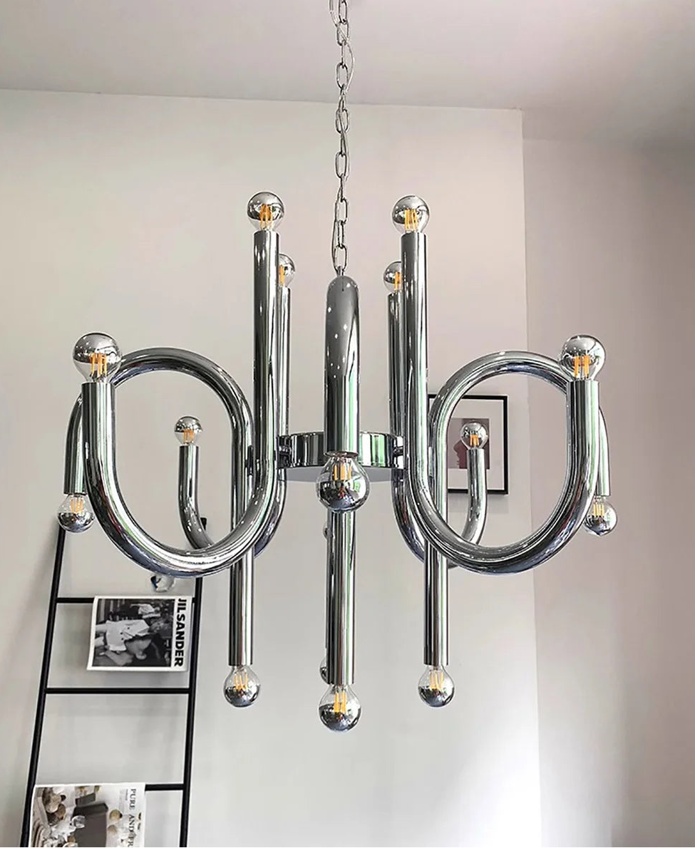 Modern chrome chandelier hanging in a room with a ladder and framed pictures.