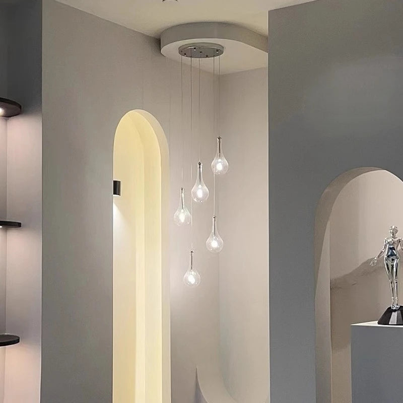 A cluster of five clear glass teardrop pendant lights hanging in a modern interior.