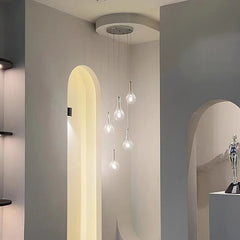 A cluster of five clear glass teardrop pendant lights hanging in a modern interior.
