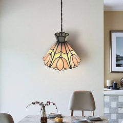 A glass floral pendant light with pink and yellow accents hanging above a dining table.