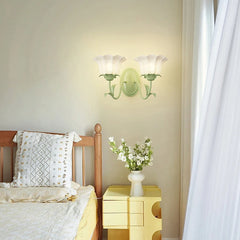 A green floral wall sconce with two frosted glass shades installed above a bed next to a yellow nightstand.