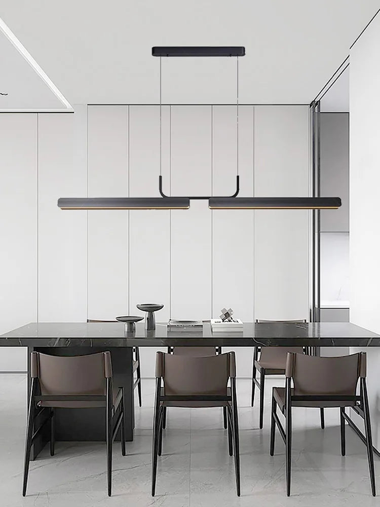 Modern dining area with a black table and chairs under a pendant light in a minimalistic setting.